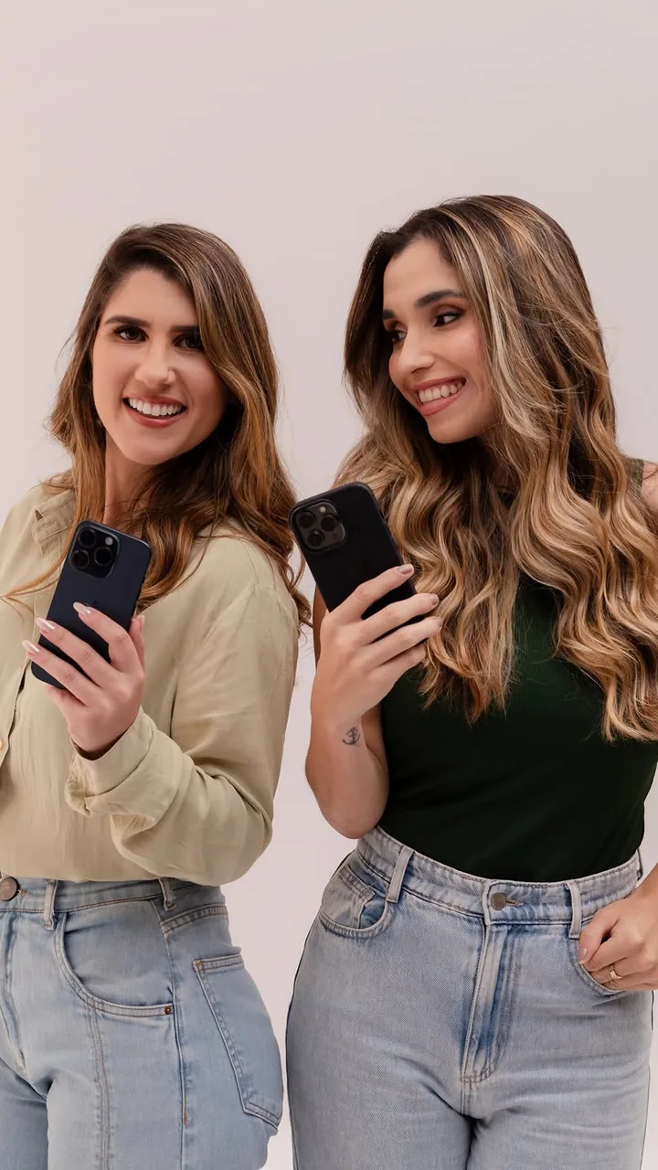 Duas mulheres segurando celulares em ensaio fotográfico